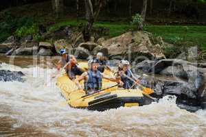 The rapids are vivacious but they enjoy the challenge. a group of young male friends white water rafting.