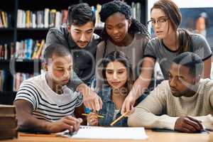 Teamwork makes the assignment work. a group of young students working on an assignment together in a college library.