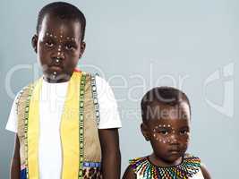 The kids of today are learning where they come from. Studio portrait shot of two young children standing together against a grey background.