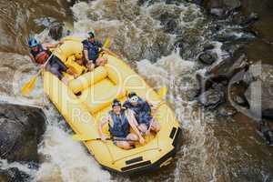 Brace yourself, here comes the next rapid. a group of young male friends white water rafting.