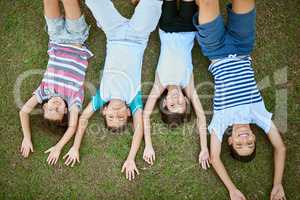 Who better to share a childhood with than siblings. High angle portrait of a group of happy siblings lying together on the grass.