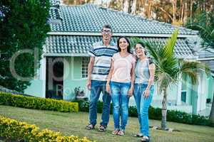 Nothing feels as good as coming back home. Portrait of a happy young woman standing together with her mother and father in their backyard.