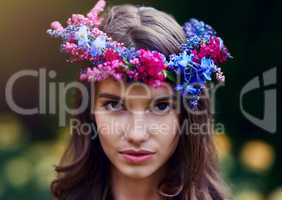 Flower crown fit for a queen of nature. Portrait of a beautiful young woman wearing a floral head wreath outdoors.