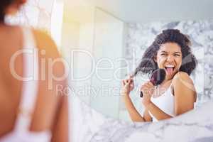 Feel fabulous, look fabulous. an attractive young woman singing while brushing her hair in the bathroom at home.