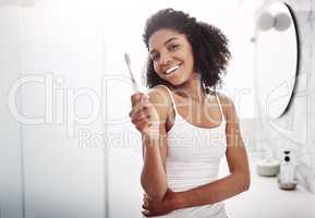 Your smile is the curve that sets everything straight. Portrait of an attractive young woman brushing her teeth in the bathroom at home.