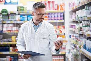 Managing a successful pharmacy. a mature pharmacist doing inventory in a pharmacy.