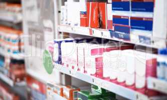 Visit us with your prescription or for something over-the-counter. shelves stocked with various medicinal products in a pharmacy.