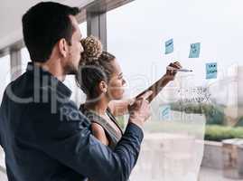 Growing their business together. a group of businesspeople brainstorming on a glass wall in an office.