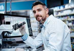 Lets make some discoveries. a mature man using a microscope while conducting pharmaceutical research.