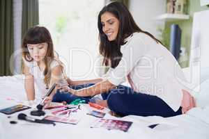 Time for some girly fun. a mother and her little daughter playing with makeup on the bed at home.