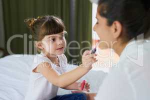 Shes a little makeup artist in the making. a mother and her little daughter playing with makeup on the bed at home.