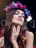 Beauty is an enchanting thing. a beautiful young woman wearing a floral head wreath outdoors.