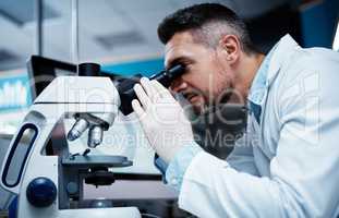 Staying one step ahead of illness with his research. a mature man using a microscope while conducting pharmaceutical research.