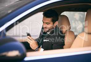 Doing business while on the move. a handsome young businessman sending a text message while on his morning commute to work.