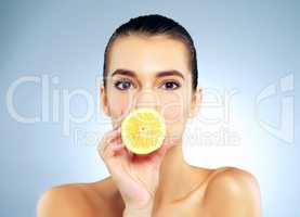 The natural way to clear up the complexion. Studio portrait of a beautiful young woman covering her mouth with a lemon against a blue background.