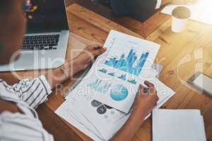 Predicting her future profits. Closeup shot of an unrecognizable businesswoman analyzing graphs in an office.