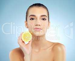 My beauty gift from the garden. Studio portrait of a beautiful young woman holding a lemon against a blue background.