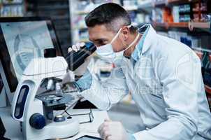 Developing effective new drugs is what he does. a mature man using a microscope while conducting pharmaceutical research.