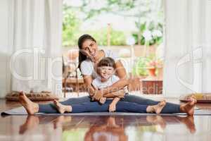 Nothing like the bond between a mother and daughter. Portrait of a cheerful young mother and daughter doing a yoga pose together while holding each other in a spit position.