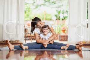 Mother and daughter quality time. Portrait of a cheerful young mother and daughter doing a yoga pose together while holding each other in a spit position.