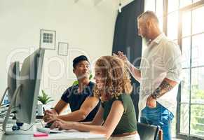 Getting some advice from his supervisor. two young creative businesspeople working on a computer in their office under the guidance of their manager.