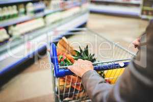 Making sure she buys the healthiest. a woman pushing a trolley while shopping at a grocery store.