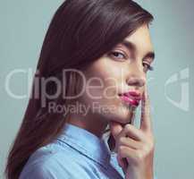 Youre sworn to secrecy. Studio portrait of an attractive young woman posing with her finger on lips against a grey background.