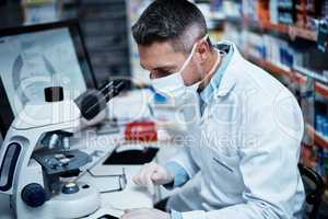 Qualified to conduct quality research. a mature man using a microscope while conducting pharmaceutical research.
