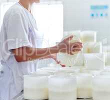 Getting them ready for packaging. an unrecognizable woman working in a cheese factory.