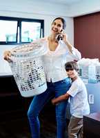 Sorry I cant come, Im doing laundry with my boy. a young attractive mother doing laundry with her son at home.