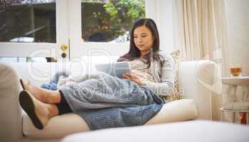 Got to rest before the baby comes. a pregnant woman using a digital tablet at home.