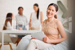 Trendy designer relaxing on beanbag chair while smiling, laughing and working on digital tablet in a creative startup agency. Portrait of a cool, comfortable and happy business woman browsing online