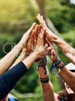 Lets go rafting. a group of unrecognizable peoples hands raised in the air to form a huddle together outside during the day.