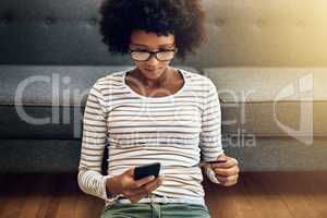 This is way more easy and convenient. a focused young woman doing online banking with her phone while being seated on the floor next to a couch at home.