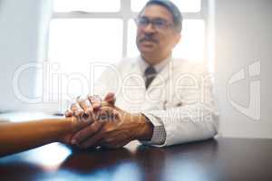 Your wellbeing is my deepest concern. a mature doctor holding a patients hand in comfort.