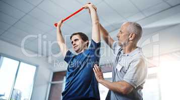 Theres no reason to make your injuries an impediment. a physiotherapist helping a patient stretch with resistance bands.