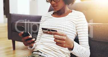 So many things to pay for. a focused young woman seated on the floor while doing online shopping on her computer in the living room at home.