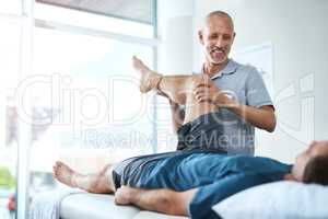 Well heal your injury in no time. Low angle shot of a handsome male physiotherapist treating a patient.