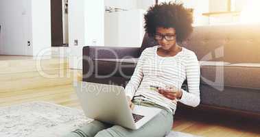 Time too pay the bills again. a focused young woman seated on the floor while doing online shopping on her computer in the living room at home.