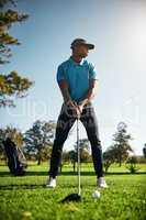 Looking at where the ball will go. a focused young male golfer about to swing and play a shot with his golf club outside on a course.