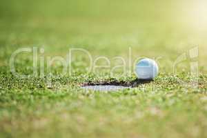 So close yet no cigar. Closeup shot of a golf ball on the edge of a hole outside on a golf course during the day.