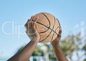 Basketball, sport and playing with a ball in the hands of a player, athlete or professional sportsperson. Closeup of a game or match outside on a court for health, recreation and fun in the sun