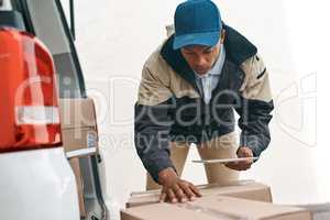 Its all digitized for easier organization. a courier using a digital tablet while sorting boxes from a delivery van.