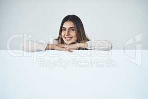 Have I got something to share with you... Studio shot of an attractive young businesswoman behind a blank placard.
