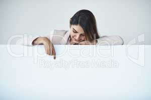 Some messages are just meant to be shared. Studio shot of an attractive young businesswoman pointing at copy space on a blank placard.