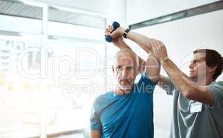 Technique is key. a young male physiotherapist helping a client with stretching exercises in his office during the day.