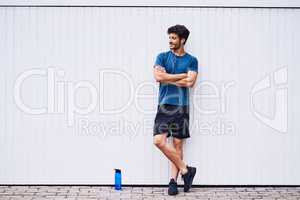 Keeping a cool sense of casual during his fitness journey. a sporty young man standing against a white wall.