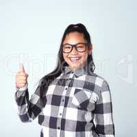 Yes I love it. Studio portrait of a cute young girl giving thumbs up against a gray background.