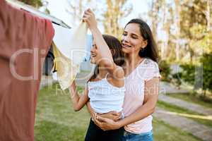 Do everything with love, even laundry. a mother and daughter hanging up laundry together outside.