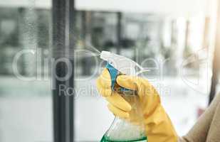 Clean, wash and day chores at home with a household hygiene spray bottle for windows inside. Closeup of cleaning job, washing and working hand with gloves spraying glass cleaner with care indoors